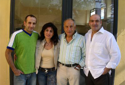 Three men and a woman posing in front of a shop window
