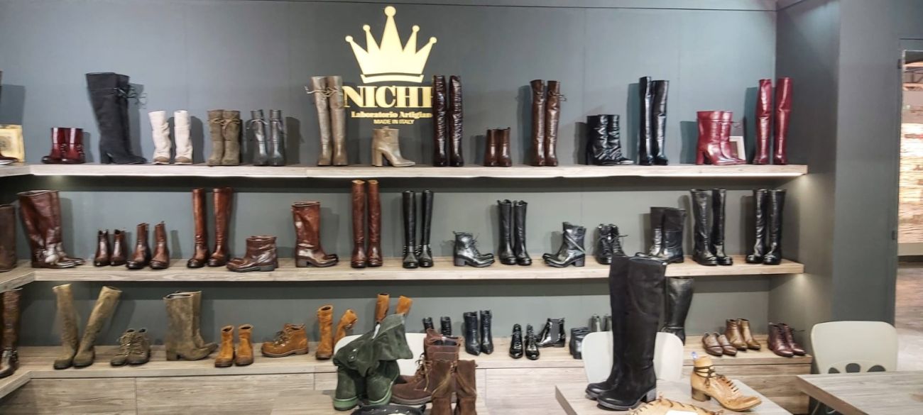 Lo stand Niche a MICAM Milano con stivali in pelle esposti sui ripiani